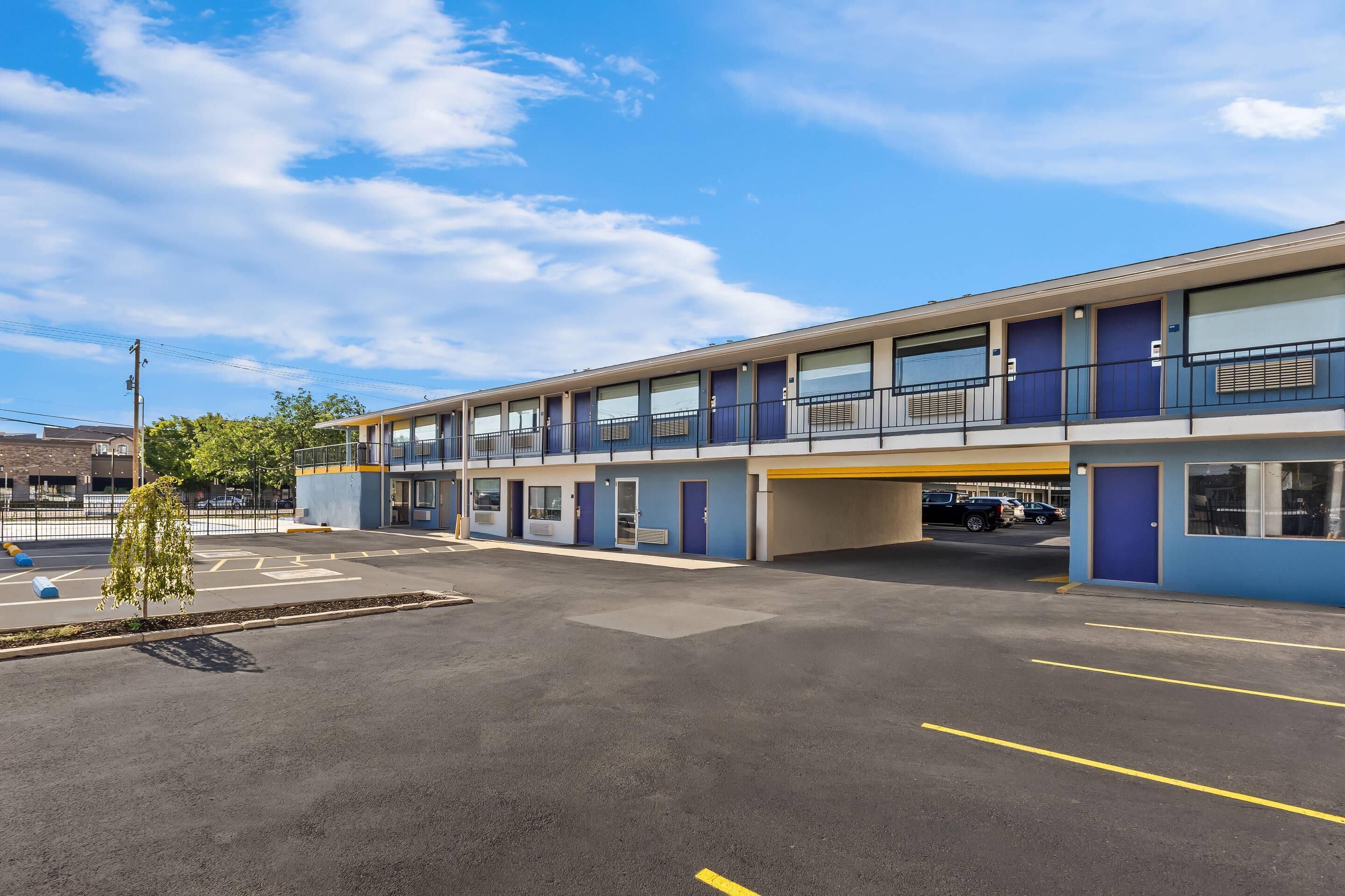 A motel with a parking lot and a single-story building with multiple rooms.
