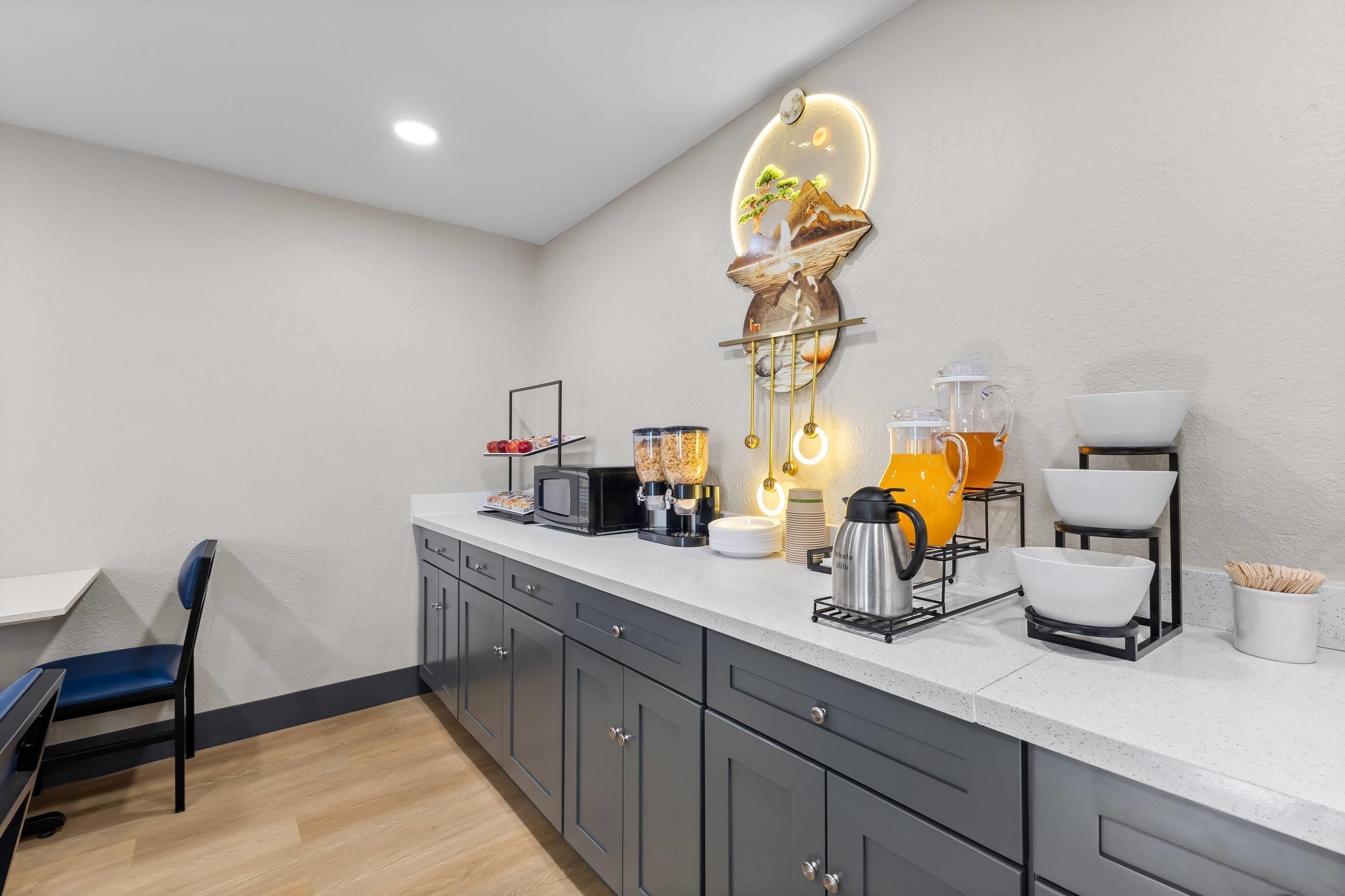 A modern kitchen with a microwave, coffee maker, and kettle on the counter.