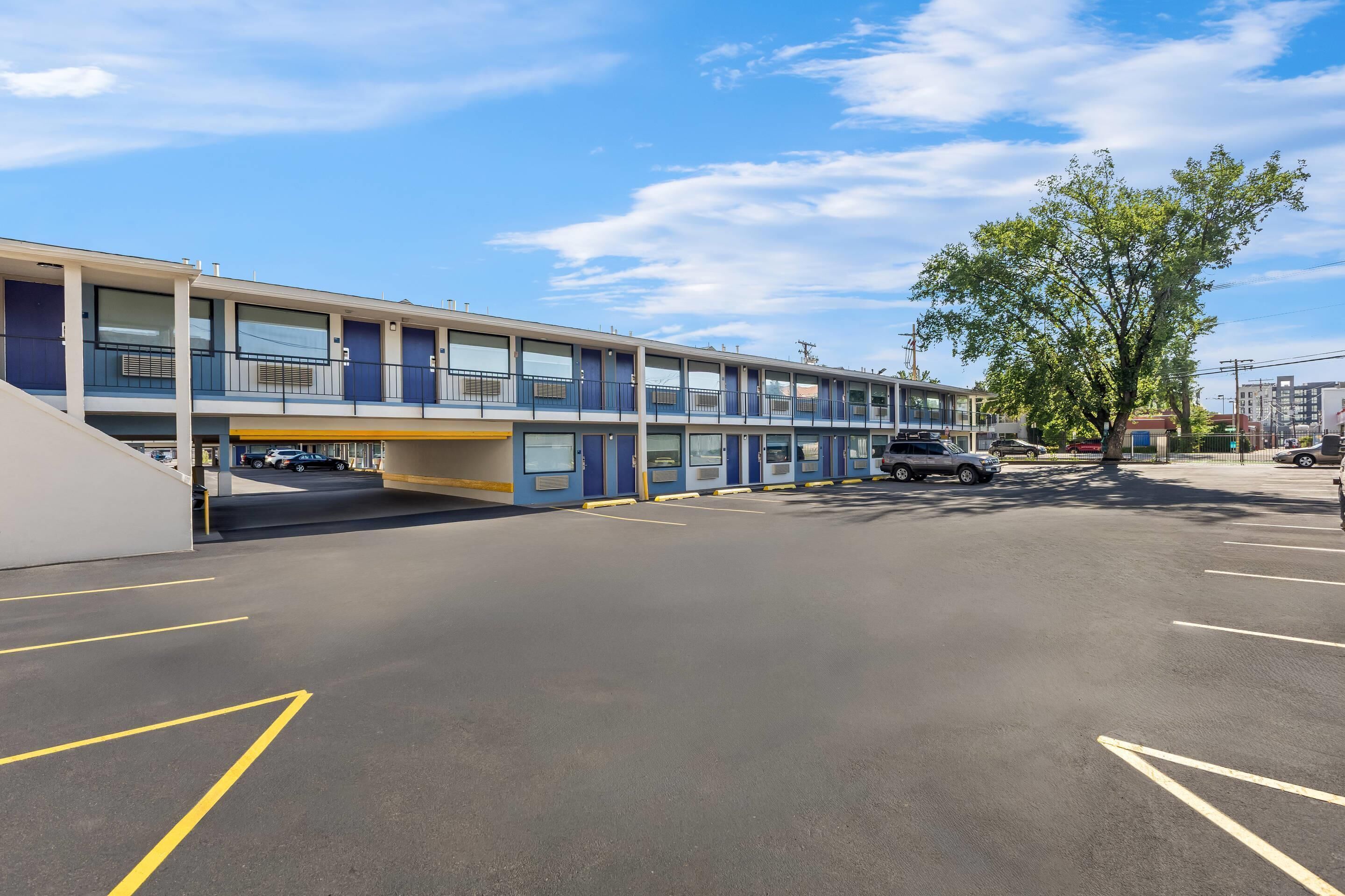 A multi-story parking garage with a flat roof and a building with blue doors and windows.