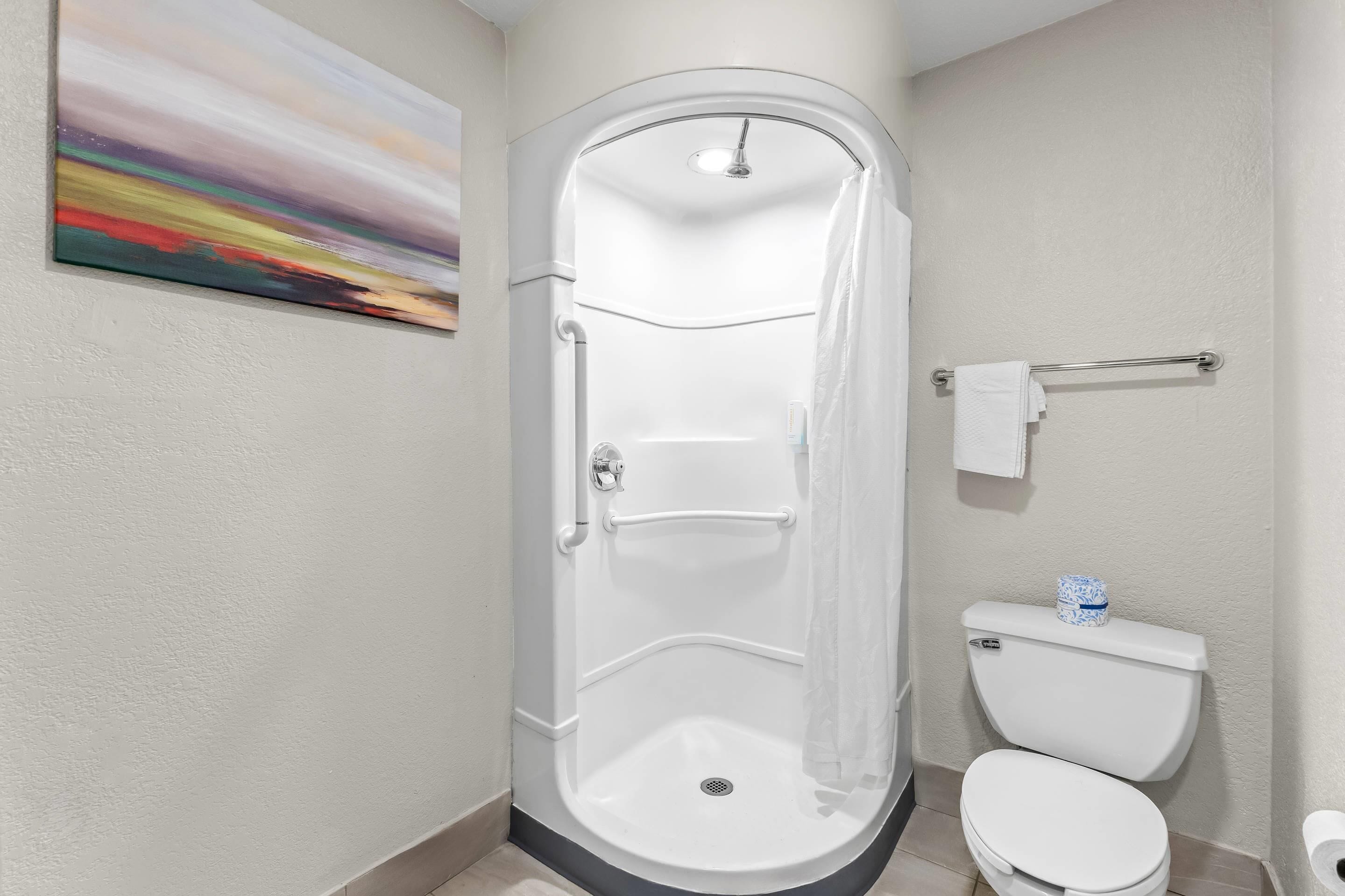 Een moderne badkamer met een inloopdouche, toilet en een handdoekhouder.