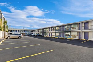 Un motel de varios pisos con espacios de estacionamiento y cielo despejado.