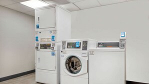 A laundry facility with stacked washers and dryers, control panels, and a water dispenser. - Motel 6 Fort Lauderdale, FL (Fort Lauderdale)