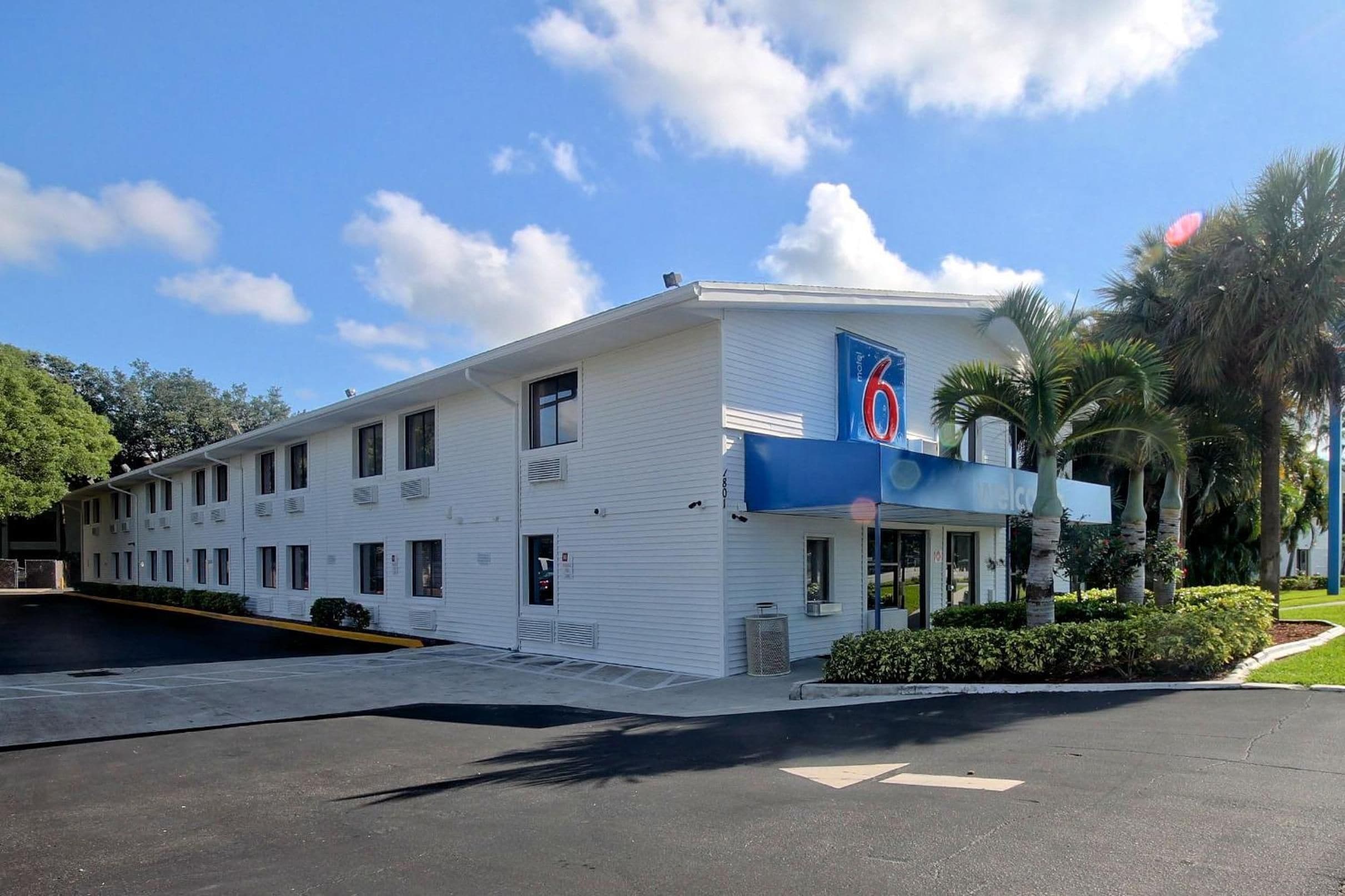 Un motel con fachada blanca, un toldo azul y un letrero con el número 6.