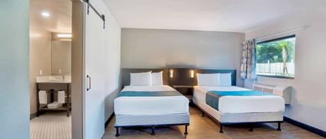 Habitación de hotel con dos camas, un baño y una ventana con cortinas.