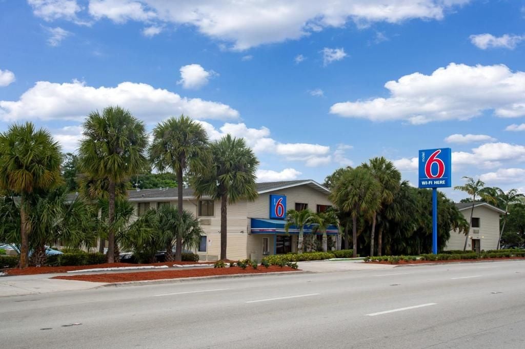 Een motel met een helderblauwe lucht, palmbomen en een bord dat Wi-Fi aanwijst.