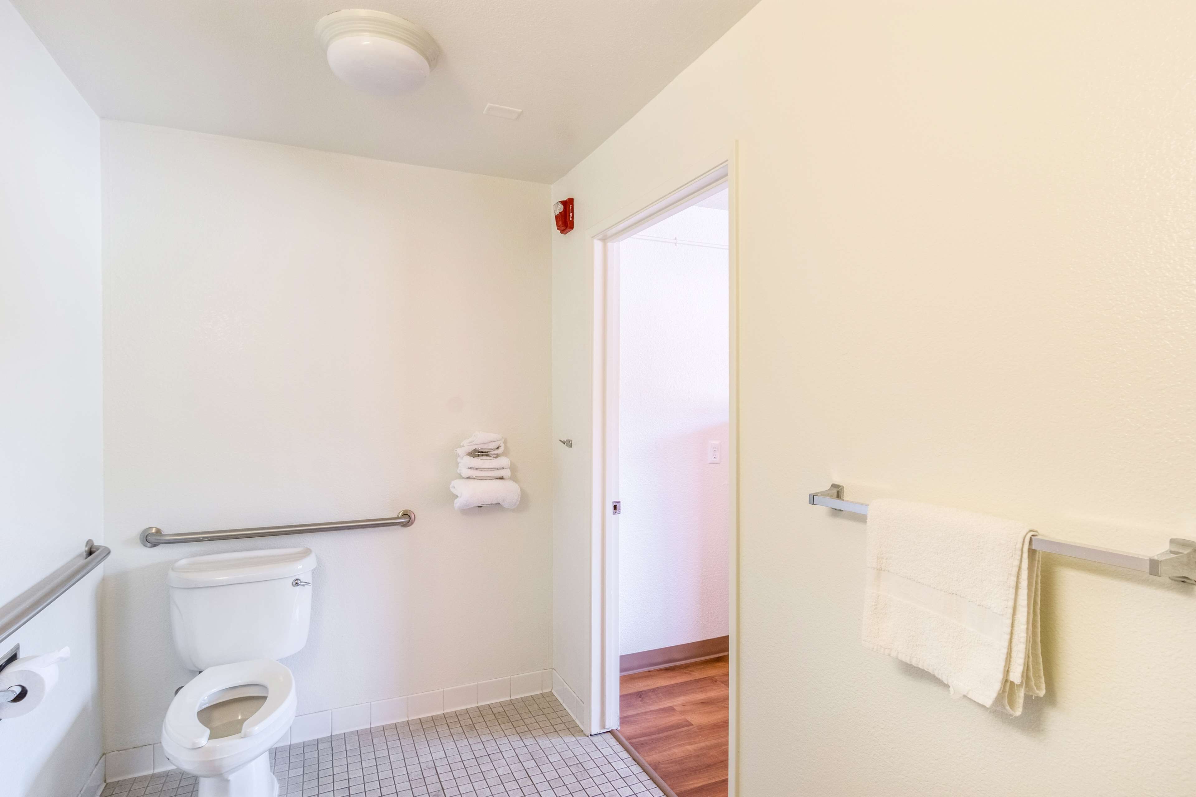 A bathroom with a toilet, grab bar, and a towel rack.