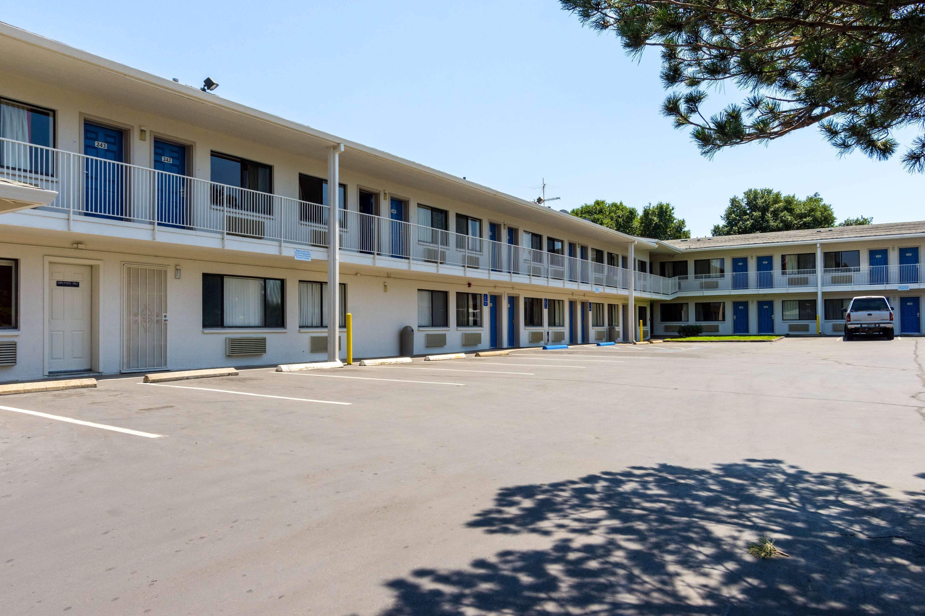 A motel with multiple rooms, a parking lot, and a small building with a blue door.