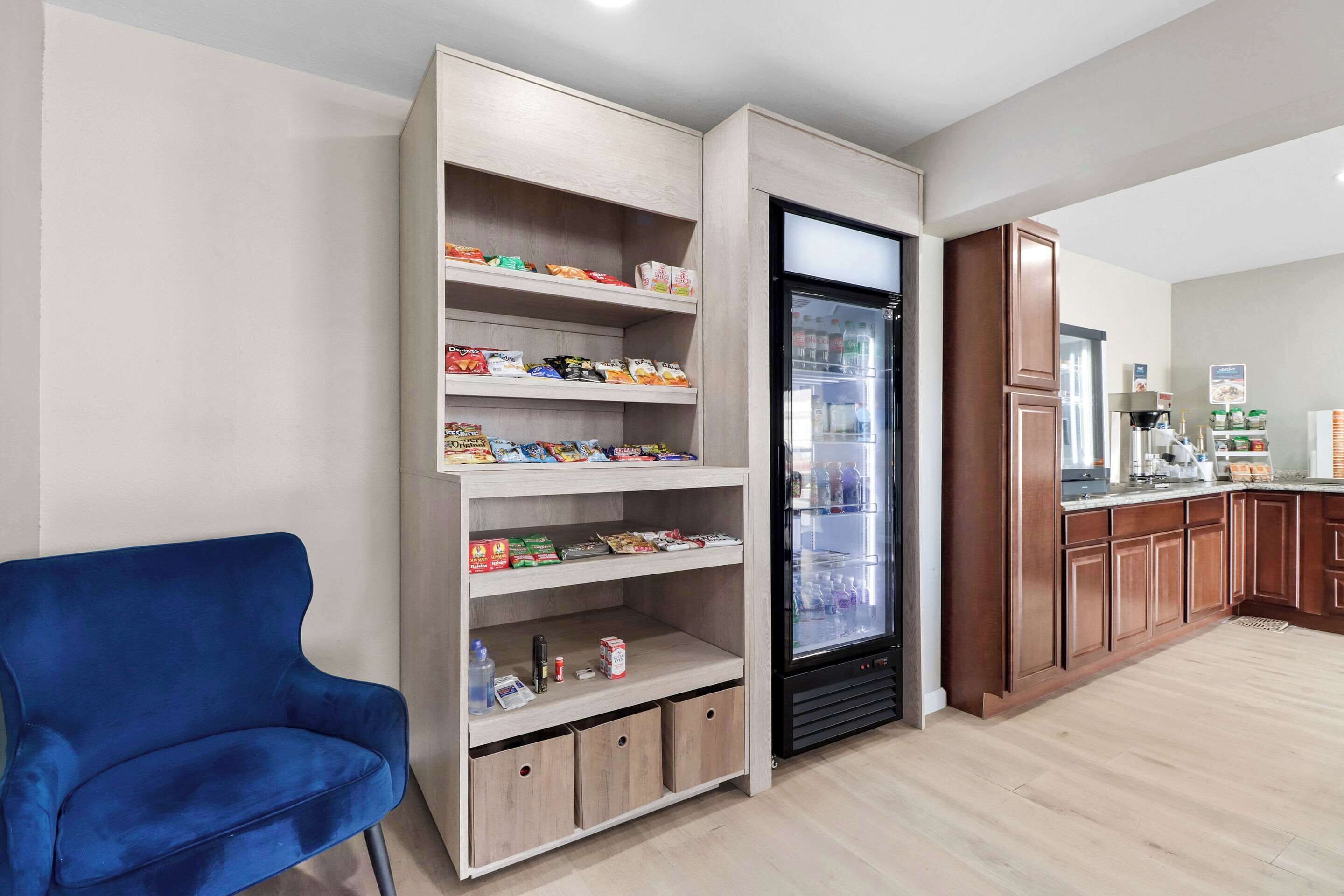 A modern kitchen with built-in shelves, a refrigerator, and a blue chair.