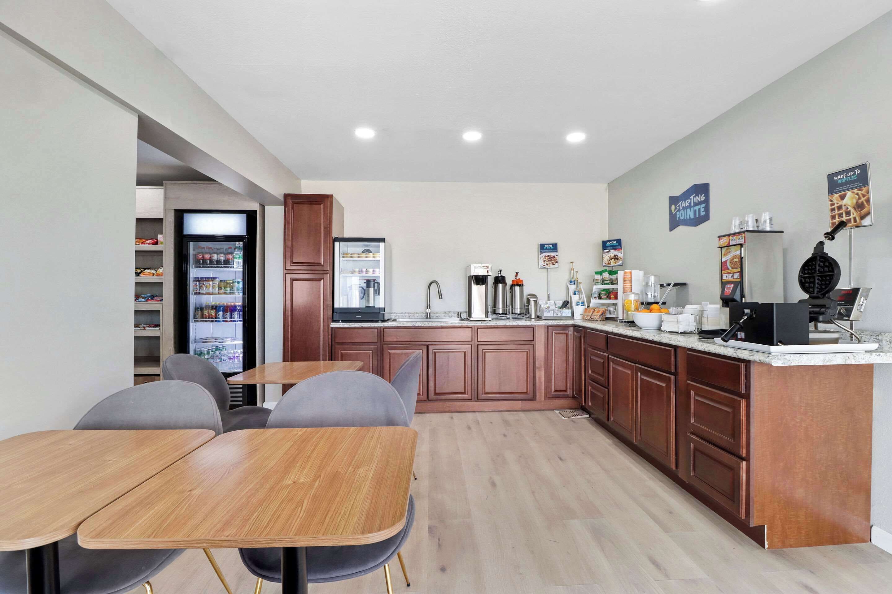 A modern kitchen with wooden cabinets, a refrigerator, a coffee machine, and a waffle maker.
