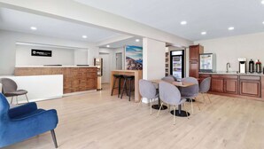 A modern hotel lobby with a reception desk, a bar area, and a dining space with grey chairs and a wooden table. - Clarion Pointe Ridgecrest near China Lake Naval Station (Ridgecrest)