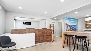 A reception area with a wooden reception desk, a white counter, and black bar stools. - Clarion Pointe Ridgecrest near China Lake Naval Station (Ridgecrest)