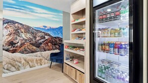 A hotel room with a mountain mural, a refrigerator stocked with beverages, and a blue chair. - Clarion Pointe Ridgecrest near China Lake Naval Station (Ridgecrest)