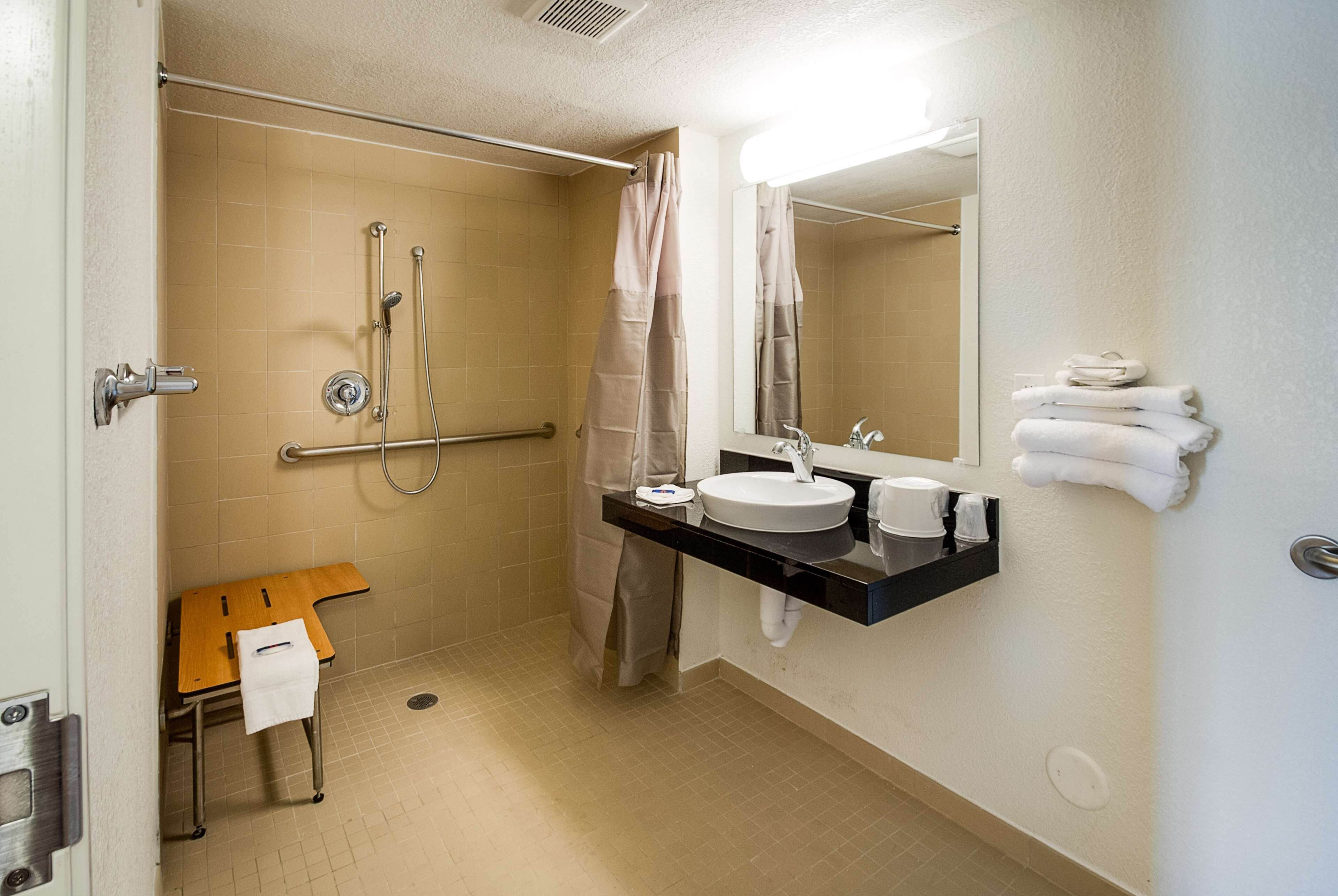 A bathroom with a shower, a sink, a mirror, and a towel rack.