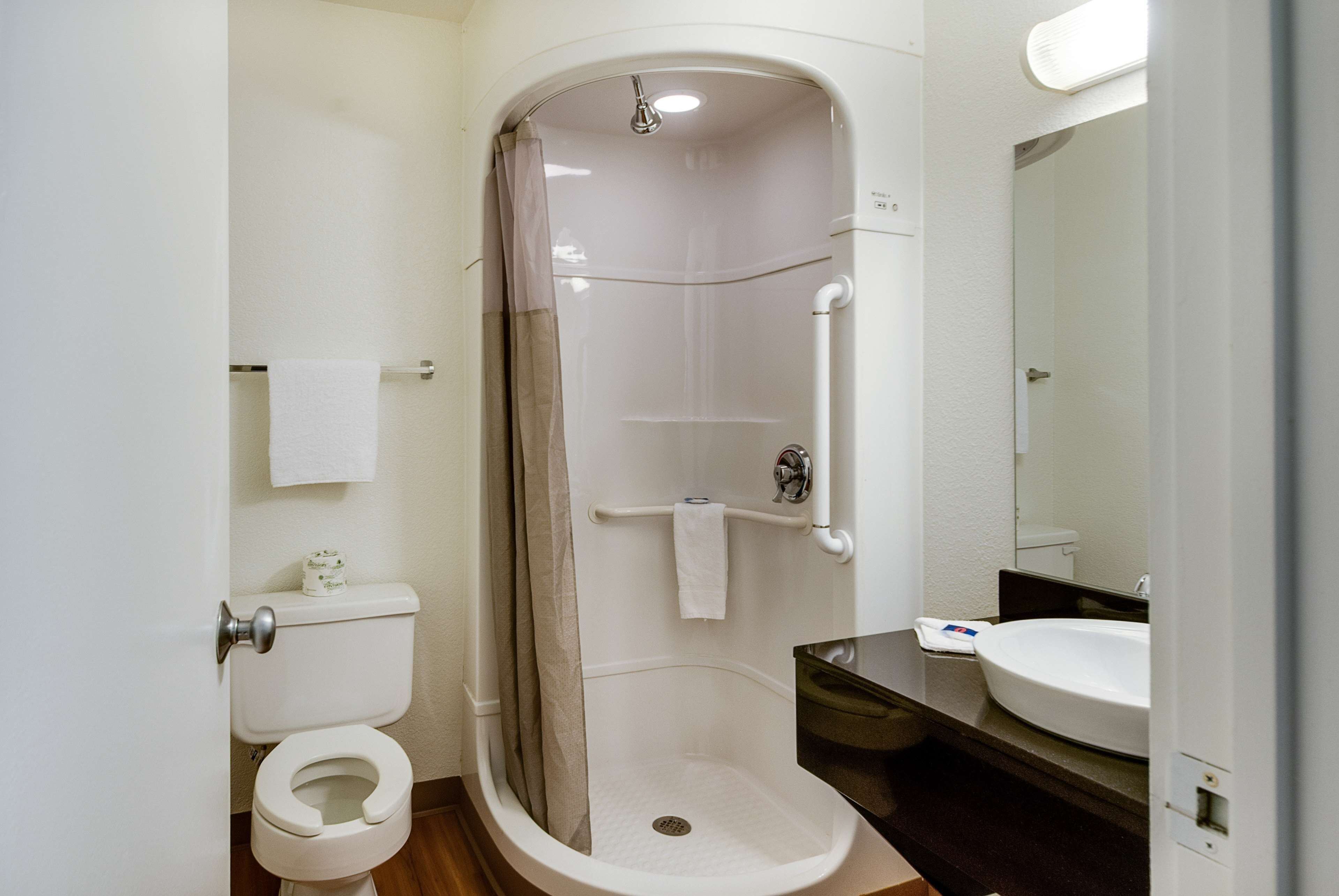 Un baño con ducha, inodoro, lavamanos y espejo.