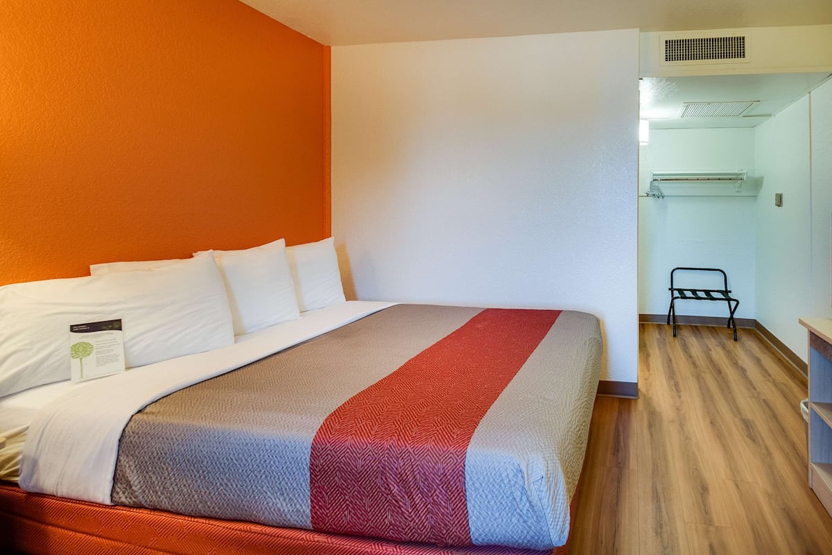 A hotel room with a bed, a wooden floor, and a shower area.