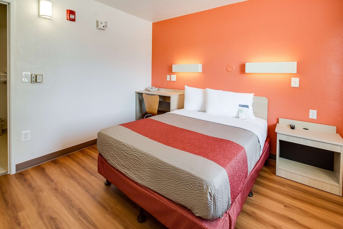 A hotel room with a bed, bedside tables, a desk, and a chair.