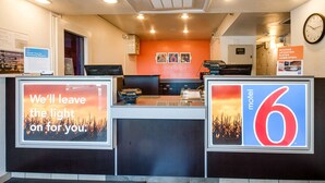 A motel lobby with a reception desk, a clock on the wall, and a sign indicating the motel number.