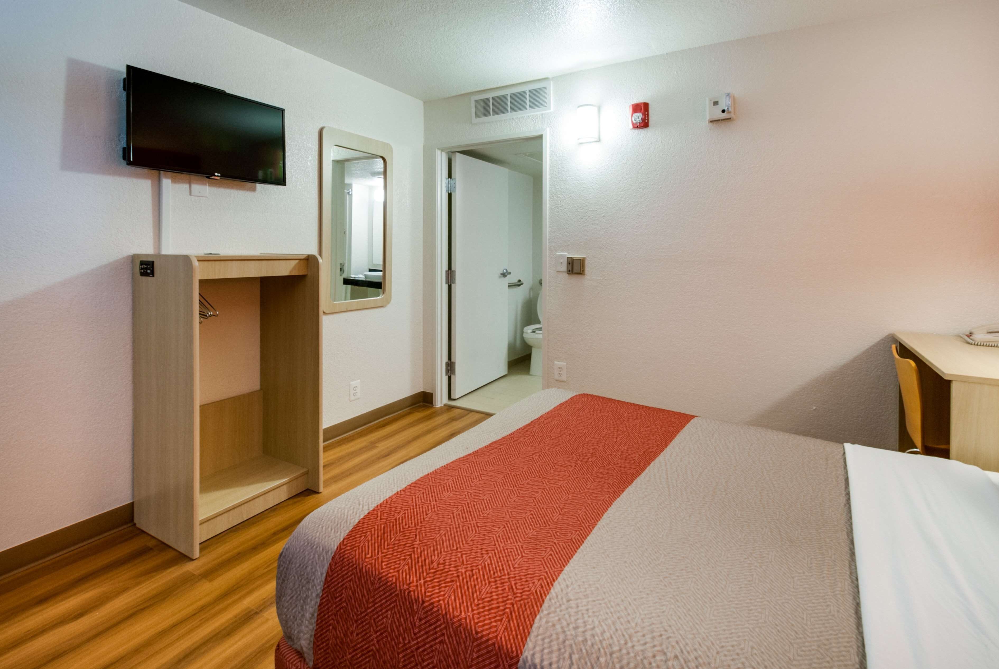 Ein Hotelzimmer mit Bett, Schreibtisch, Spiegel, Fernseher und Kleiderschrank.