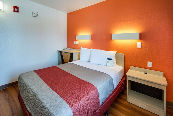 Una habitación de hotel con cama, mesitas de noche, escritorio y silla.