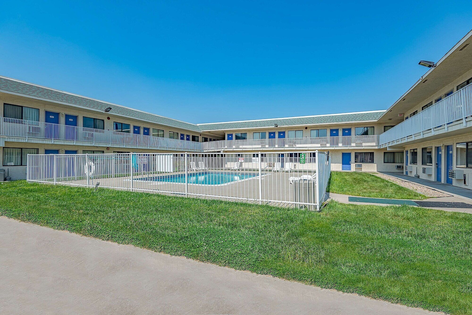 Un motel con piscina central, varios balcones y un césped bien cuidado.