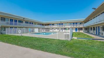 Un motel con piscina central, varios balcones y un césped bien cuidado.