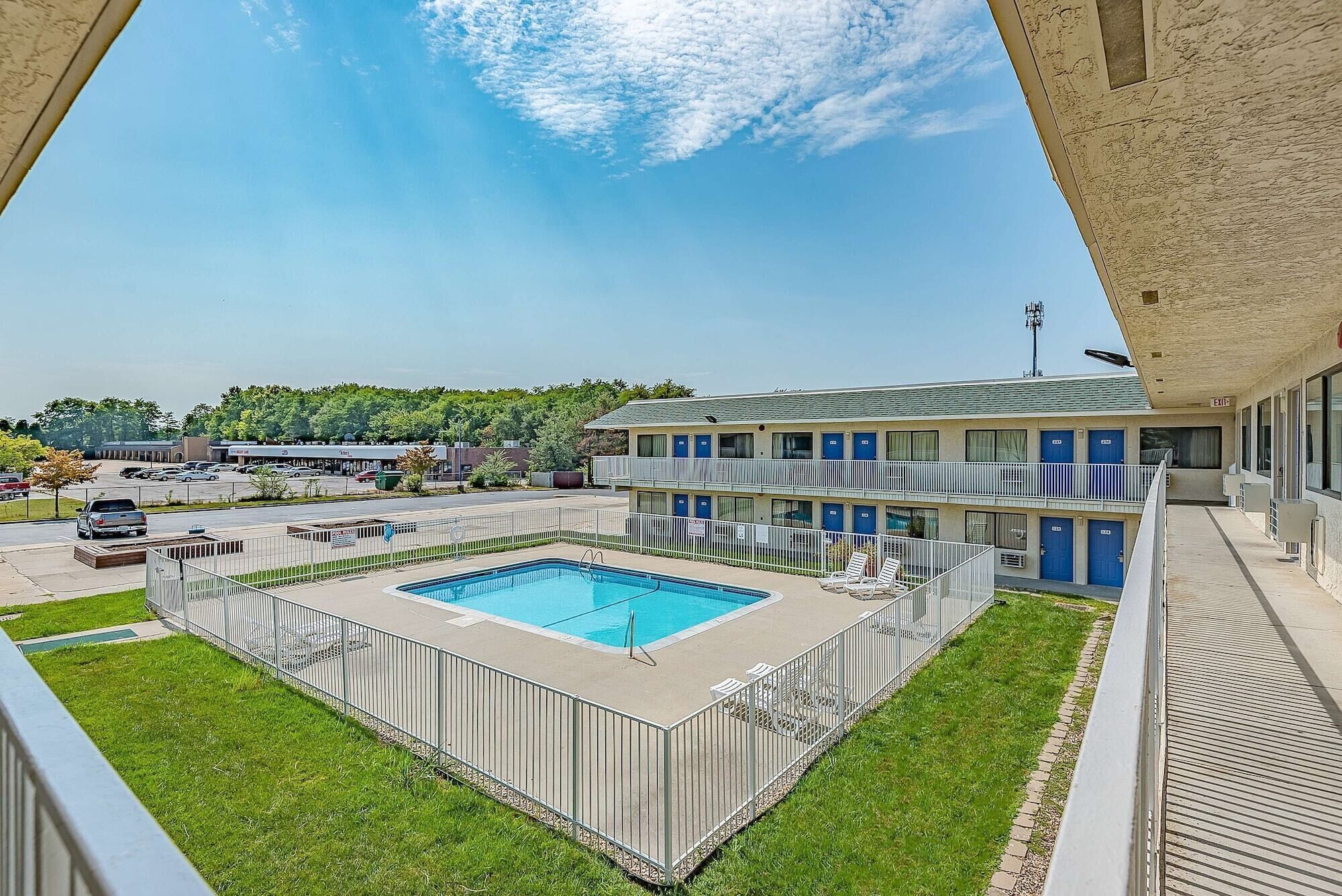 A motel with a swimming pool, a fenced deck, and a parking lot.