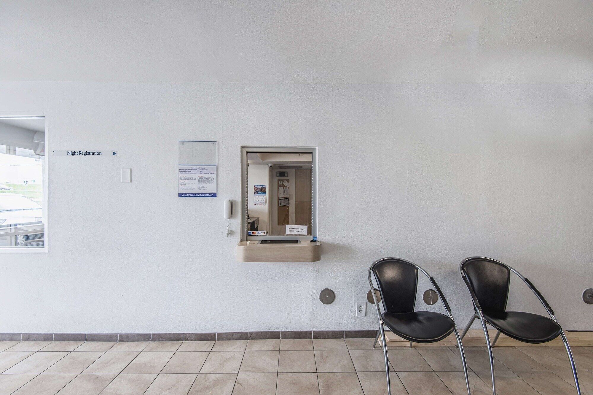 A waiting area with a sign for night registration, a phone, and two chairs.