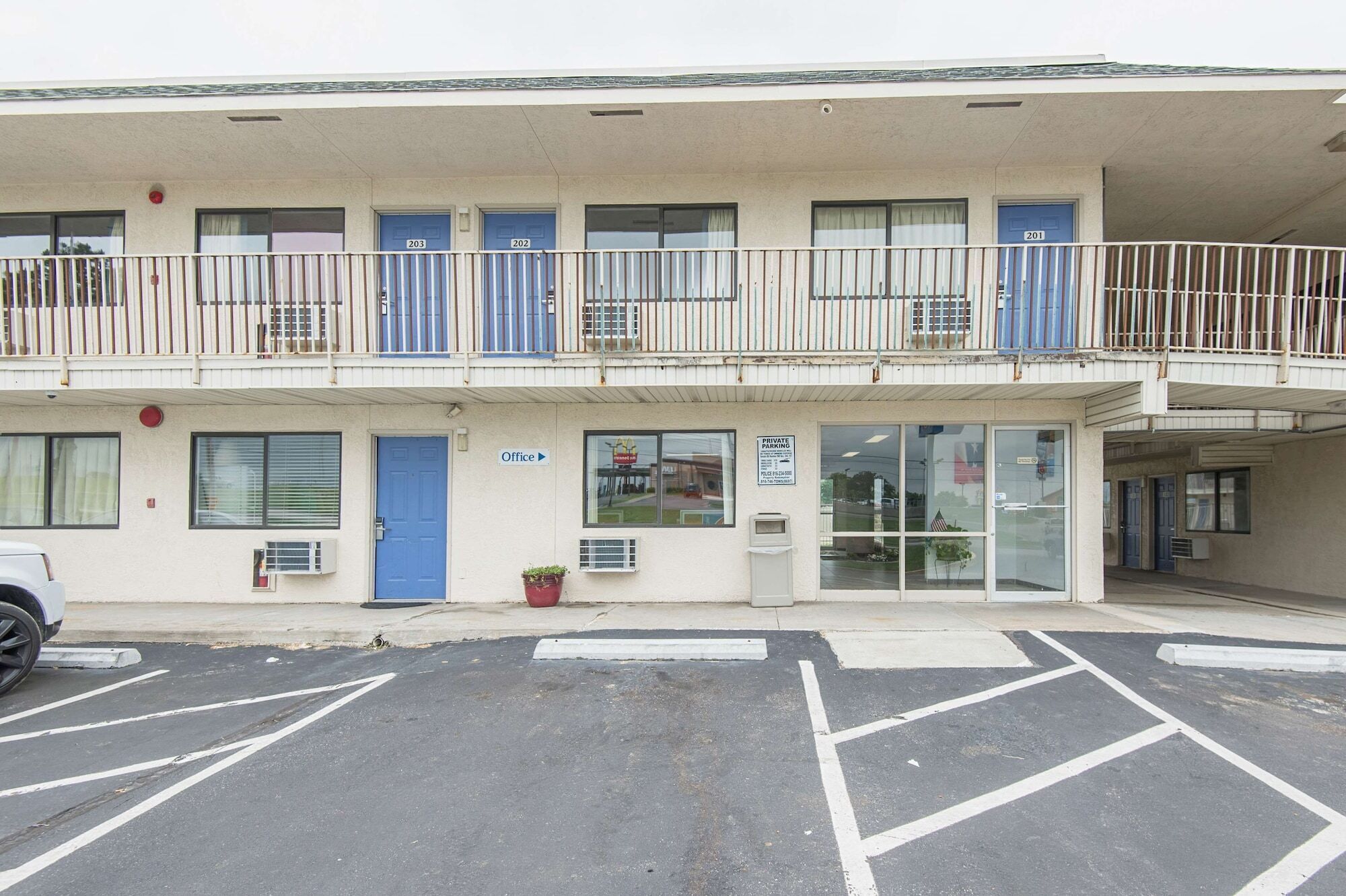 A two-story motel with numbered rooms, a visible office, and a parking lot.