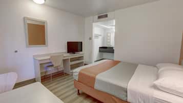 A hotel room with a bed, a desk with a chair, a television, and a mirror.