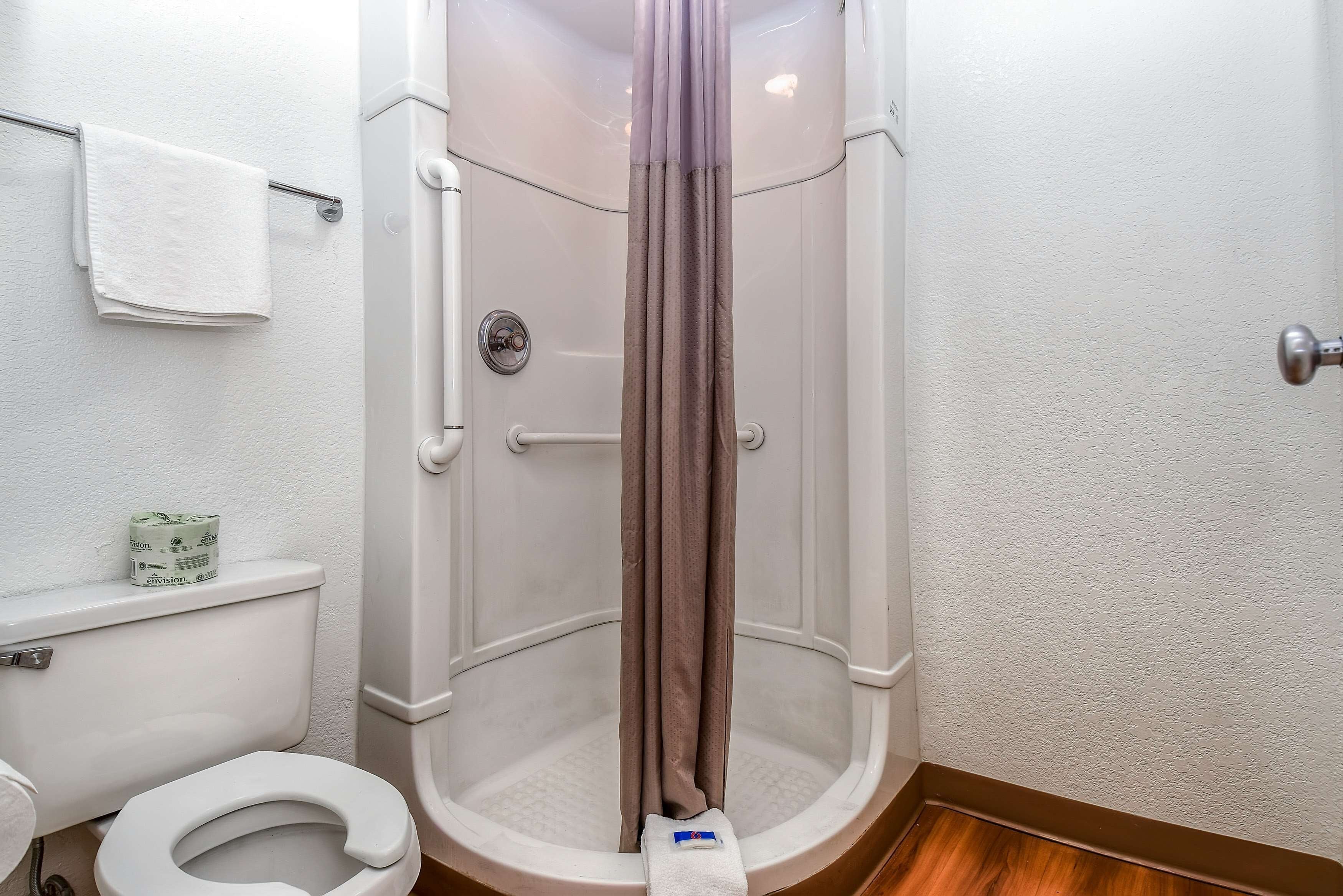 A shower with a curtain, a toilet, and a towel rack with a towel.
