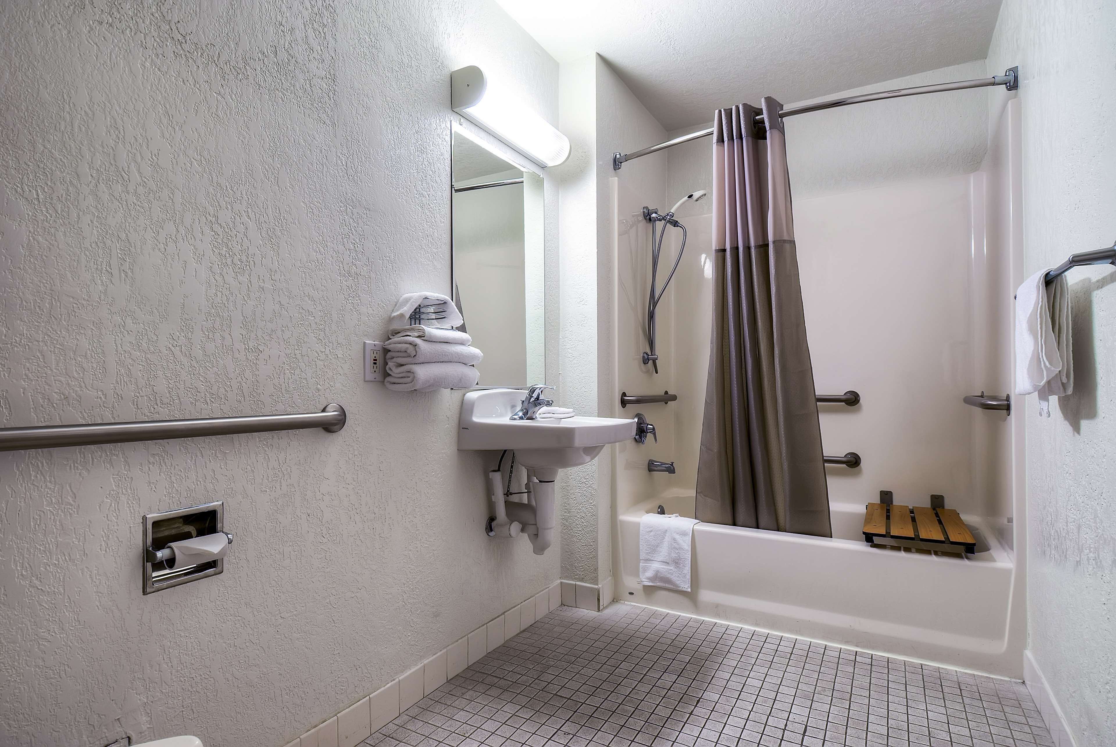 A bathroom with a walk-in shower, a sink, a towel rack, and a grab bar.