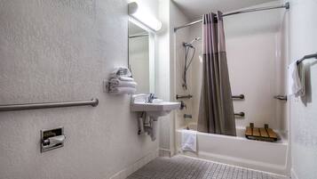 A bathroom with a walk-in shower, a sink, a towel rack, and a grab bar.