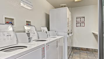A laundry area with multiple washing machines, a sign indicating responsibility for unattended items, and a wall-mounted informational sign.