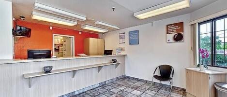 Zona de recepción con mostrador, una silla y ventana con vistas.