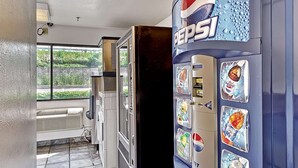 A vending machine with Pepsi branding, a window with blinds, and a vented wall. - Motel 6 Glenview, IL - Chicago North (Glenview)