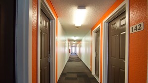 A hotel hallway with doors numbered 142, carpeted floors, and a light fixture on the ceiling.