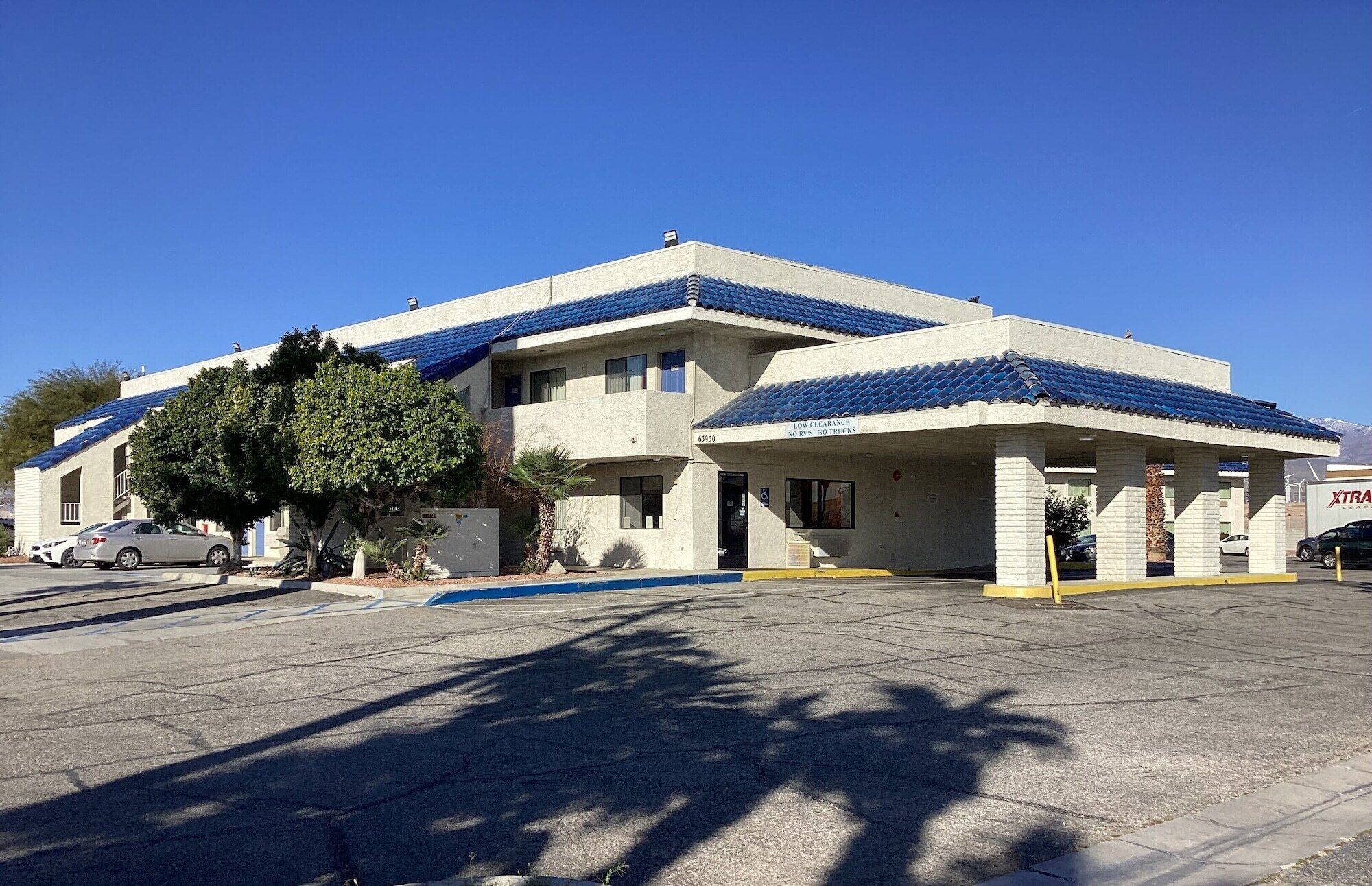 A two-story building with a flat roof and a parking area in front.