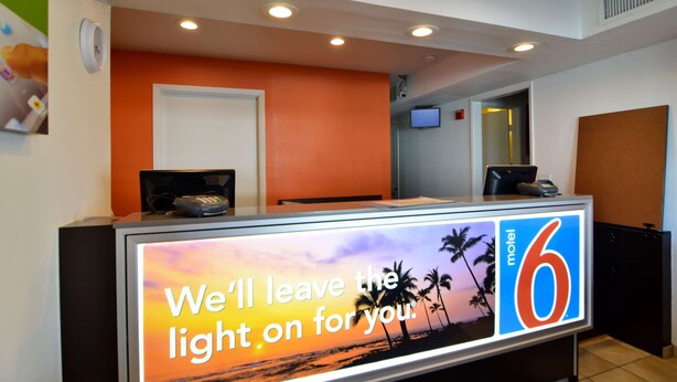 A reception desk with a digital display advertising a motel, a closed door, and a television mounted on the wall.