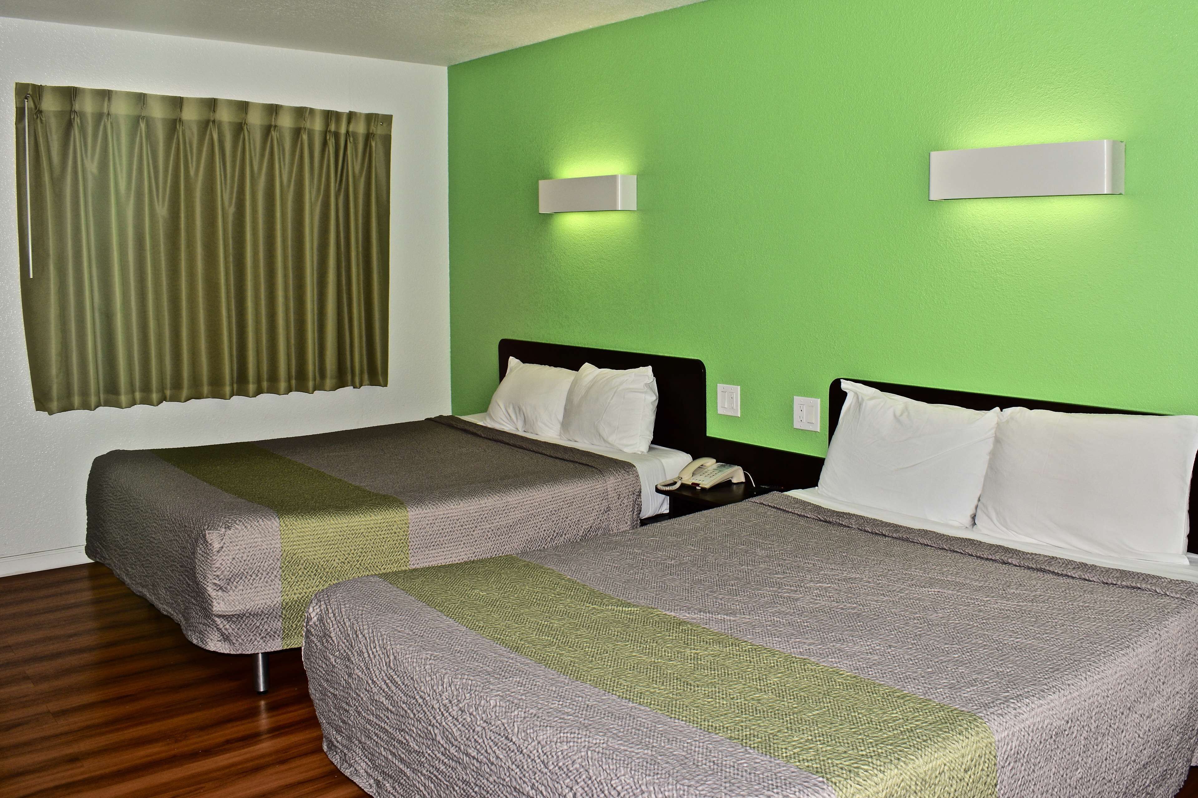 A hotel room with two beds, green walls, and a curtain.