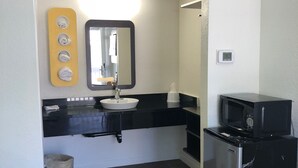 A compact kitchenette with a black refrigerator, a sink, and a microwave. - Motel 6 Barstow, CA (Barstow)