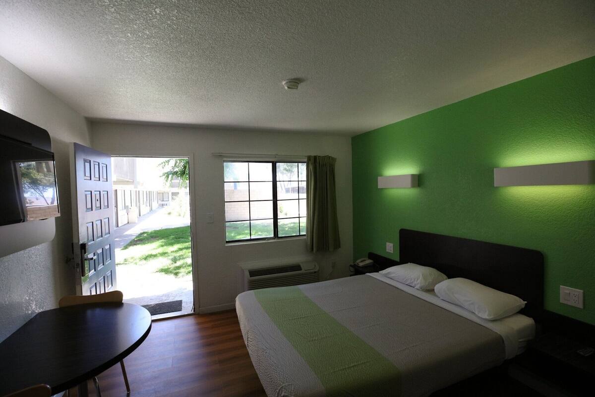 Una habitación de hotel con una cama, un escritorio y una ventana.