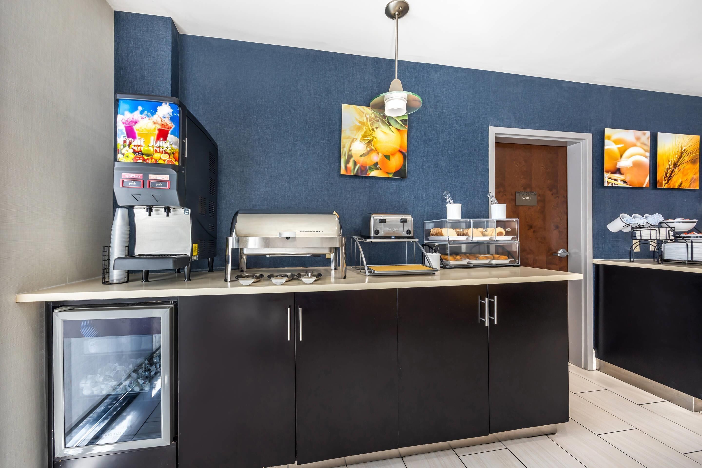 A modern kitchen area with a coffee machine, a microwave, and a refrigerator.