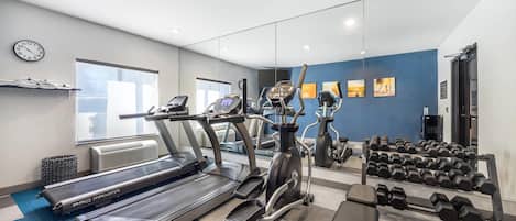 A gym with treadmills, an elliptical, and dumbbells.