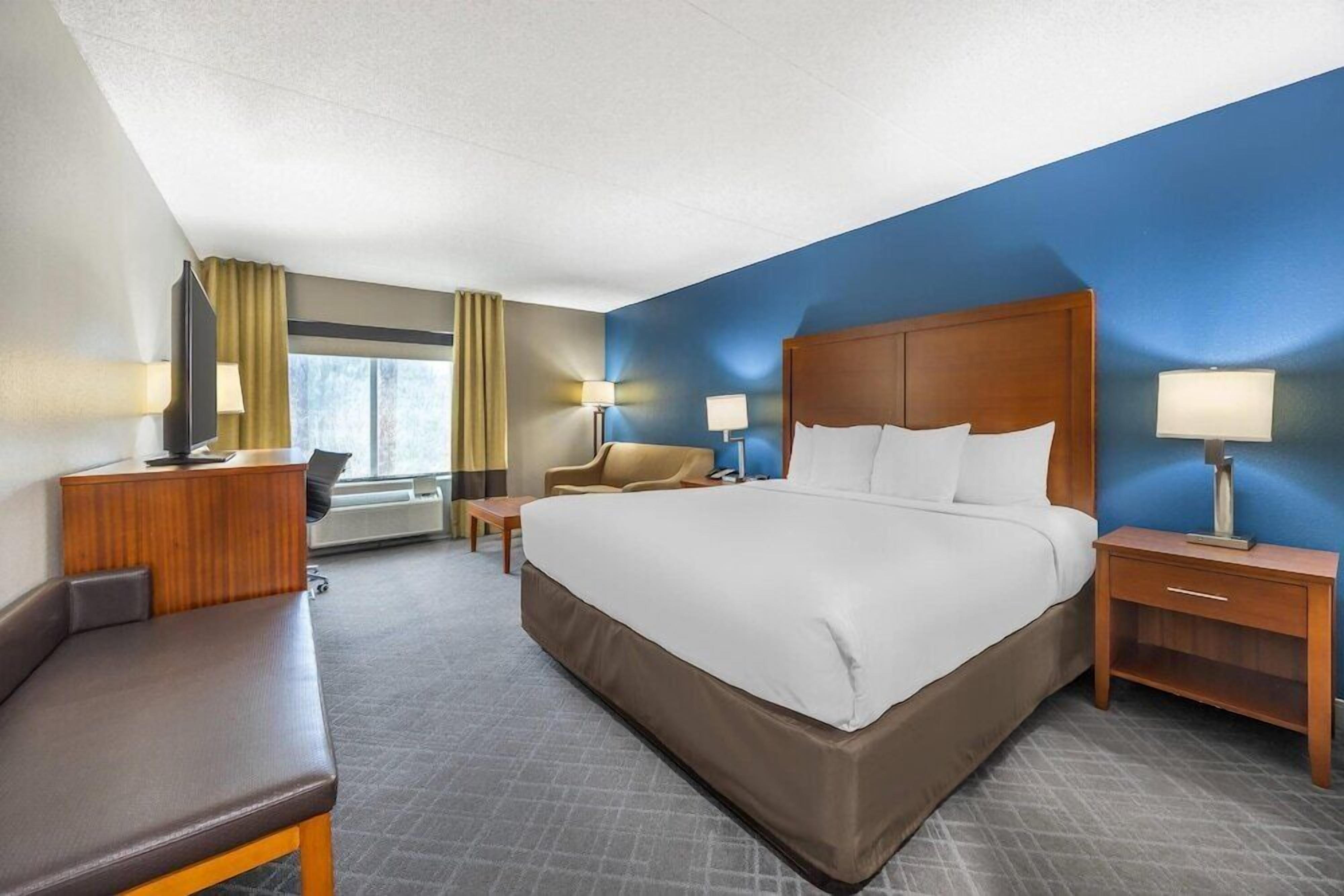 Une chambre d’hôtel avec un grand lit, un bureau, une chaise et un téléviseur.