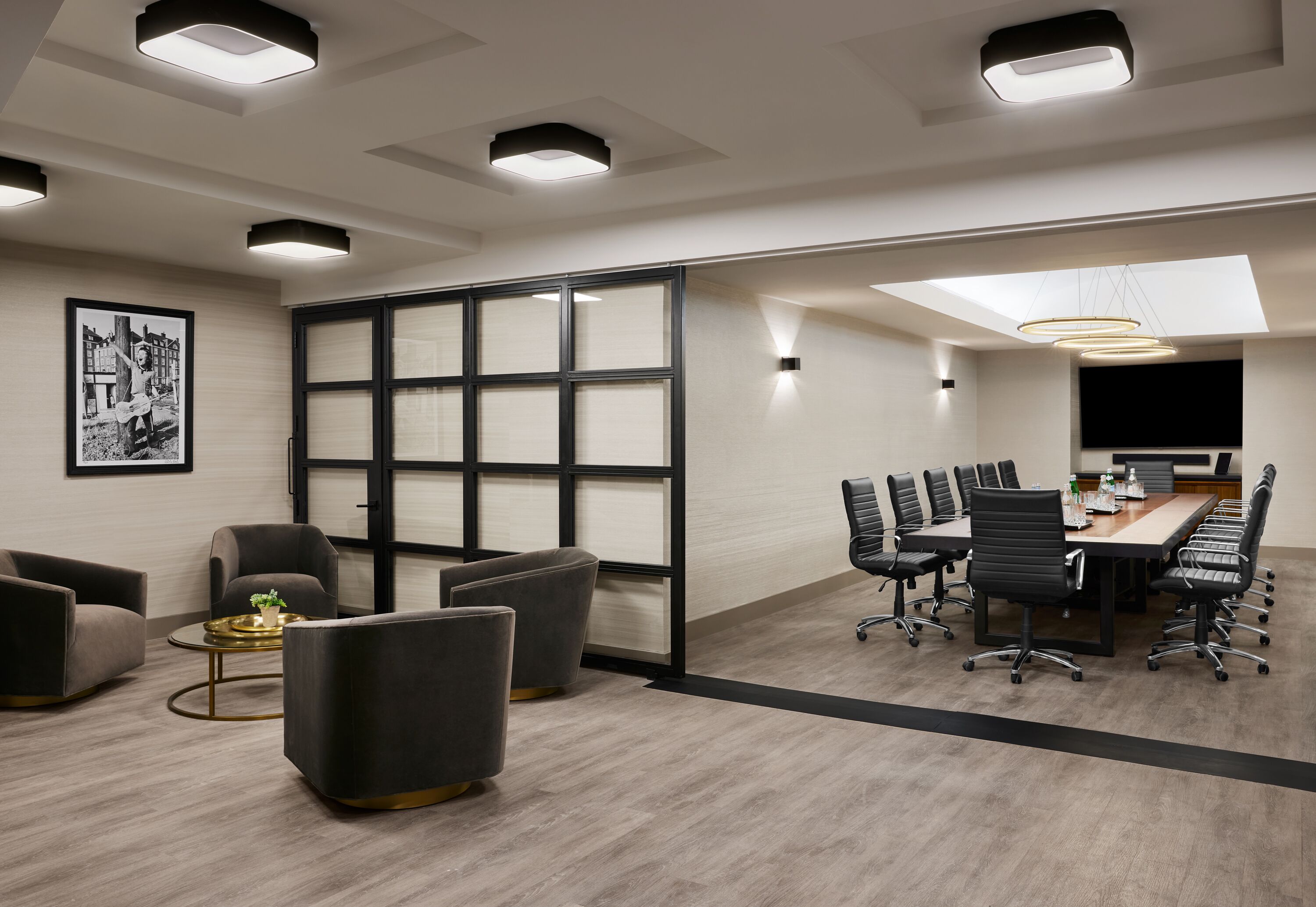 A modern conference room with a large table, black office chairs, and a glass partition.