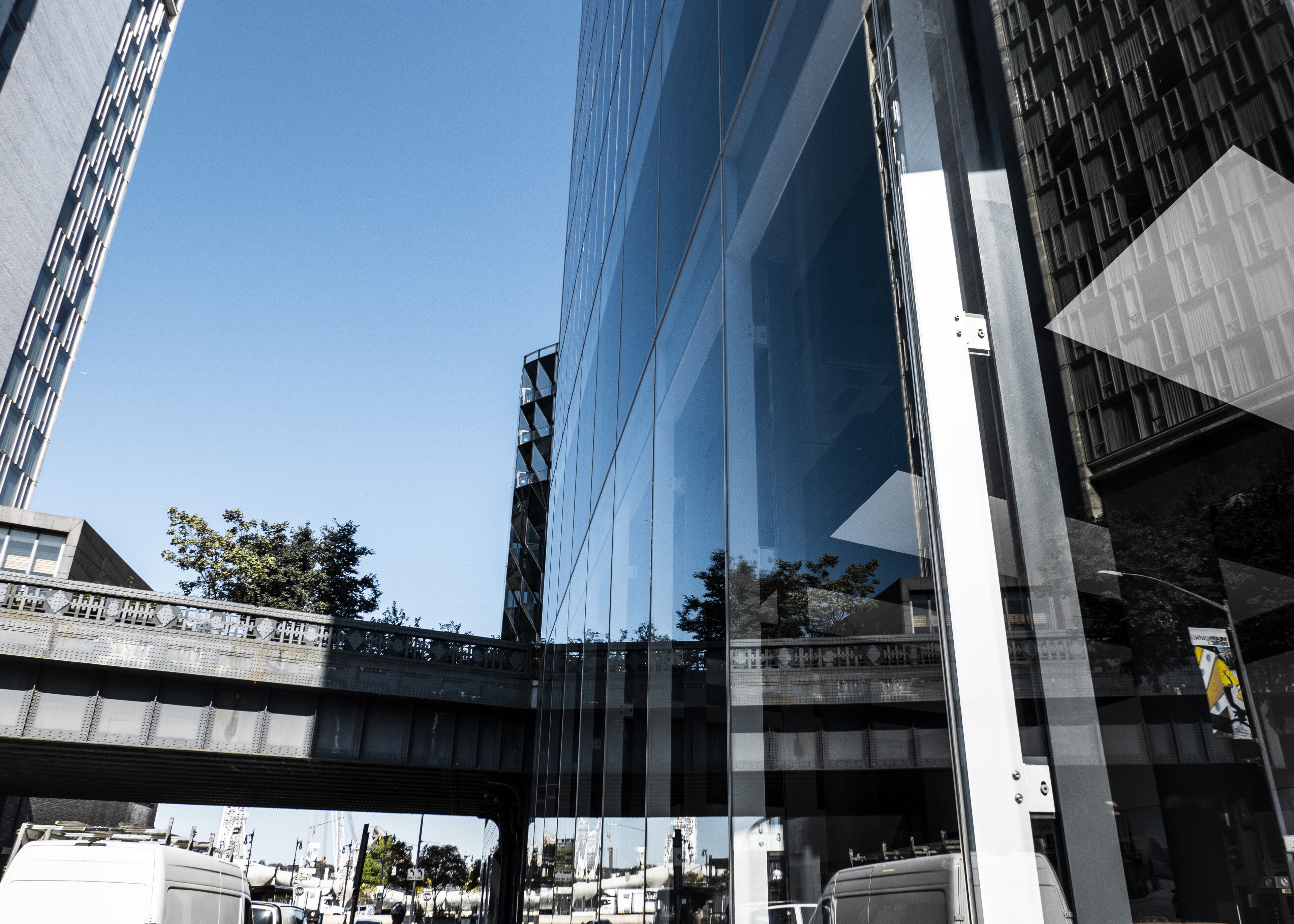 A modern building with a glass facade and a bridge in the foreground.
