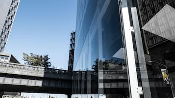 A modern building with a glass facade and a bridge in the foreground.