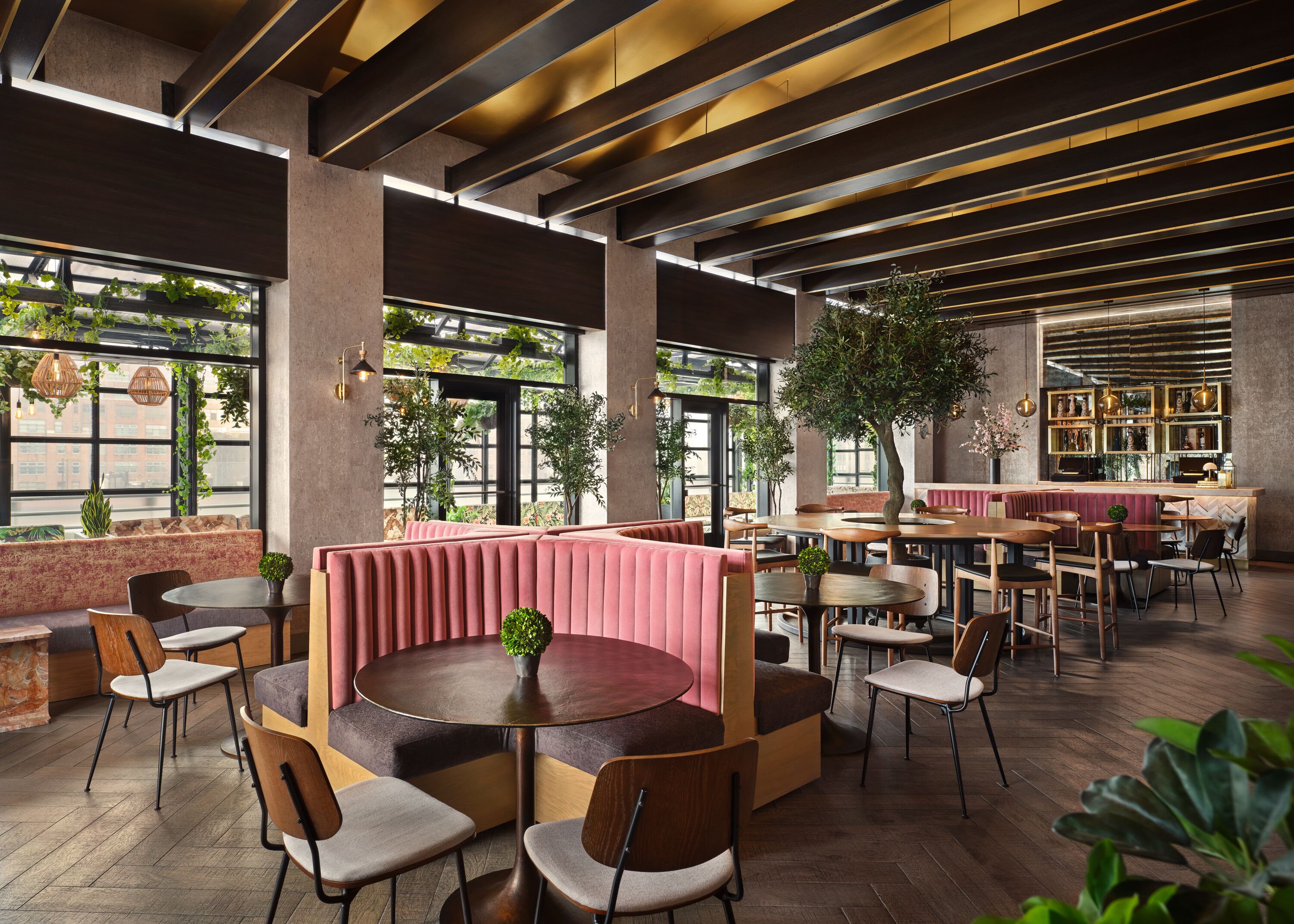 Un café moderne avec des planchers en bois, des tables rondes et des banquettes dotées de sièges rembourrés.