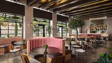 Un café moderne avec des planchers en bois, des tables rondes et des banquettes dotées de sièges rembourrés.