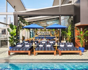 Una piscina al aire libre, sombrillas, sillones reclinables de piscina